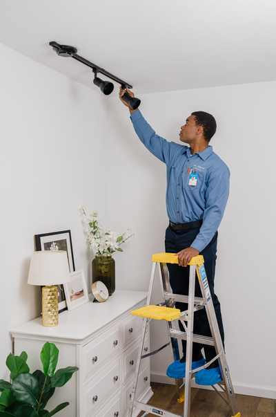 An electrician hangs a lighting fixture.